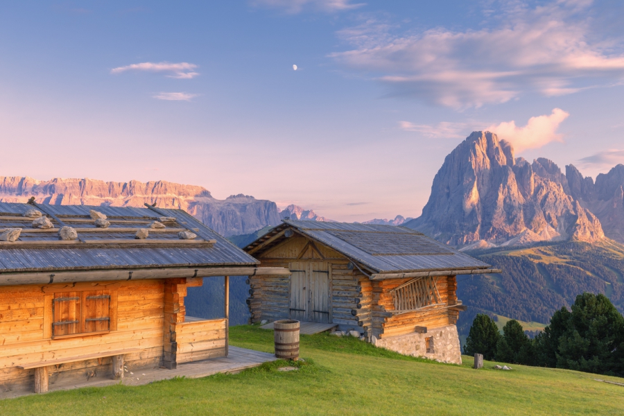 Baite tradizionali con vista sul Sassolungo e il gruppo del Sella al tramonto, Dolomiti